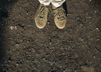 Khaki-colored moccasins with light soles on a man's feet in white pants against a gray dirt road...