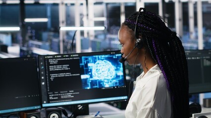 Data center computer scientist using AI assistant to provide user technical support. African american woman in server farm managing live support calls assisted by artificial intelligence, camera A