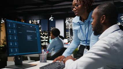 Two black workers interacting with a virtual assistant on computer at desk, AI generated responses and smart automation to improve online communication. Data driven AI solutions.