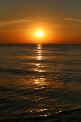 Beautiful sunset over calm ocean water with reflections in sky