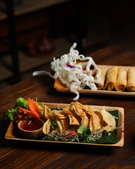 Crispy Fried Dumplings with Chili Sauce and Spring Rolls on Wooden Table