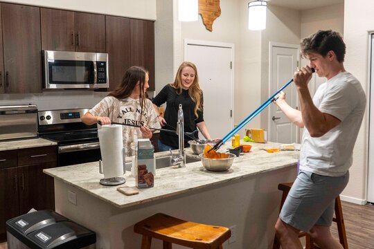 Cheerful Friends Cooking Together in Modern Kitchen
