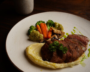 Grilled Beef Steak with Mashed Potatoes and Steamed Vegetables on Ceramic Plate