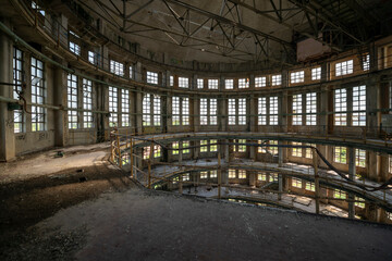 Fototapeta premium Abandoned distillery tower in Italy – circular industrial building with glass dome, steel beams, panoramic windows, decaying factory interior, urban exploration, post-industrial architecture