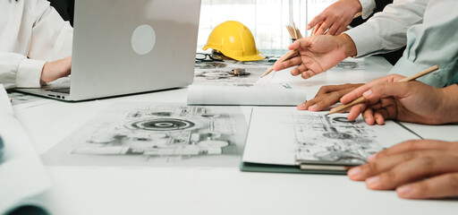 A collaborative meeting taking place in a modern office, showcasing hands actively engaged in design discussions, with a laptop and sketches spread across a table. SACTR