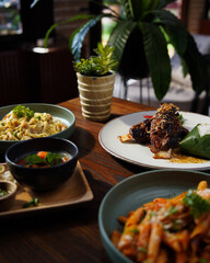 Assorted Indonesian Dishes with Mango Sticky Rice and Traditional Side Dishes on Wooden Table