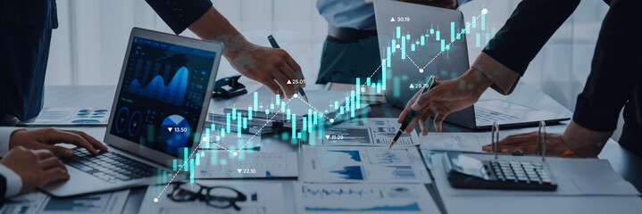 A diverse business team engaged in financial analysis, utilizing laptops and charts in a contemporary office space to drive informed decisions and strategies. Trope