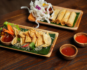 Crispy Fried Dumplings with Chili Sauce and Spring Rolls on Wooden Table