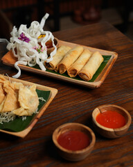 Crispy Fried Dumplings with Chili Sauce and Spring Rolls on Wooden Table