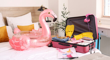 Suitcase and travel supplies on bed in room. Tourism concept