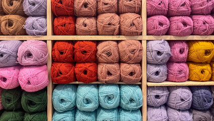 Colorful yarn balls neatly arranged in wooden shelves, showcasing a variety of textures and hues, perfect for knitting and crafting projects with warmth and creativity