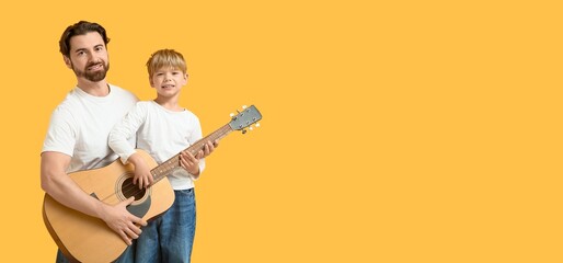 Happy dad and son playing guitar on yellow background with space for text