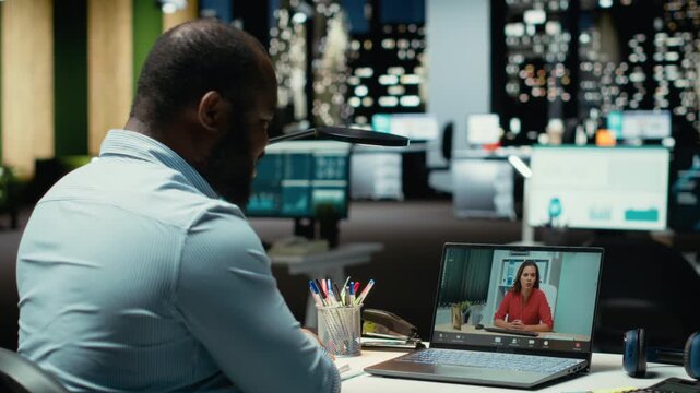 Professional male chatting late at night during online teleconference, engaged in a digital discussion for efficiency. Interacting with participants, networking session in corporation. Camera B. - Powered by Adobe