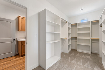 A walkin closet with shelves and a laundry room behind