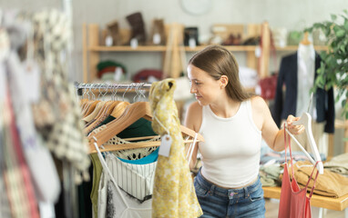 Joyful teenage girl came to the store to buy summer clothes. Buying clothes for teenagers and...
