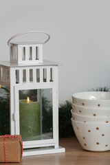 Candle with bowls and Christmas gift on table in kitchen