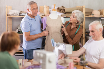 Obraz premium Group of elderly men and women sew and work with mannequin during master class