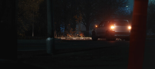 A car with its hazard lights on on a city street at night