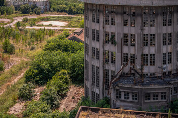 Obraz premium Abandoned distillery tower in Italy – circular industrial building with glass dome, steel beams, panoramic windows, decaying factory interior, urban exploration, post-industrial architecture