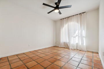 An empty room featuring a tiled floor along with a ceiling fan overhead