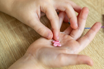 child's hands carefully thread colorful beads onto string, beading activity, developing fine motor skills, creating unique piece jewelry