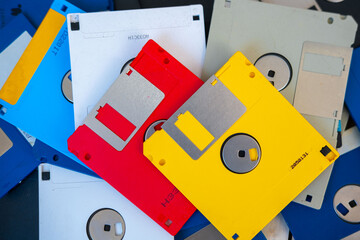 Colorful pile vintage 3.5 inch floppy disks on wooden surface, retro computing, obsolete data storage, tech nostalgia, digital history, collection old media formats 80s, 90s, nostalgic tech memory