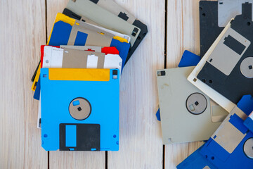 Colorful pile vintage 3.5 inch floppy disks on wooden surface, retro computing, obsolete data...