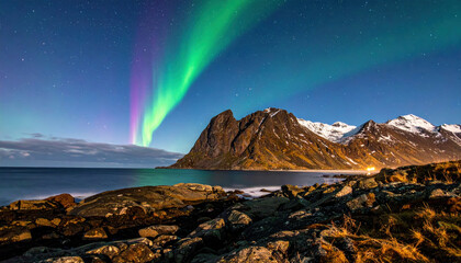 Mesmerizing display of Northern Lights illuminates night sky over rugged coastal landscape with snow capped mountains and calm sea