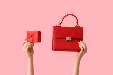 Female hands with stylish handbag and Christmas gift on pink background