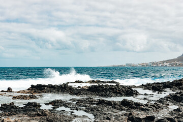A view of a small wave crashing against the rocks.