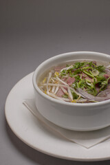 Delicious Vietnamese soup, Traditional Vietnamese beef noodle soup in steaming bowl, Freshly prepared beef pho with herbs and fragrant broth in ceramic dish