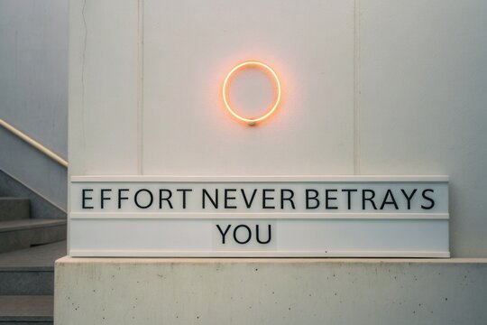Neon circle above quote Effort Never Betrays You on a wall