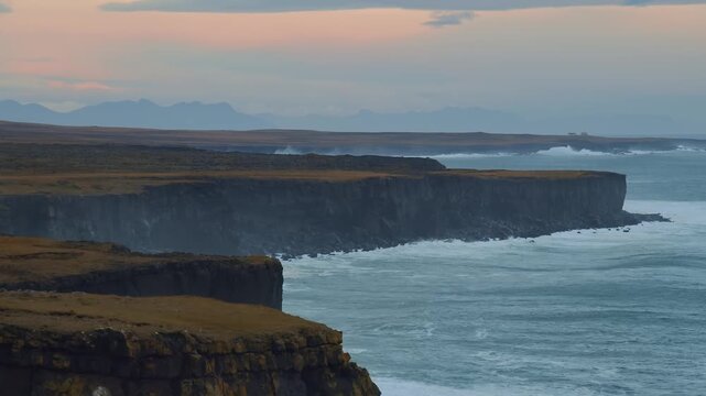 An aerial or wide shot of the dramatic L&oacute;ndrangar basalt cliffs on the Sn&aelig;fellsnes Peninsula in Iceland. The footage captures the rugged coastline, with waves crashing against the towering rock format