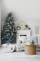 Sofa with cushion, coffee table and Christmas tree in interior of living room