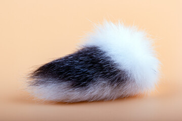 Black and white tail of a rabbit on a light peach background. Symbol of good luck. Protective amulet.