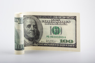 Rolled one hundred dollar bill on a white background. The concept of saving cash.