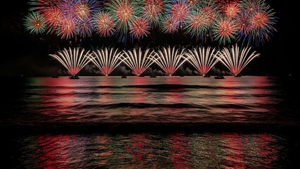 Colorful pyrotechnics illuminating the night sky, reflected in calm waters
