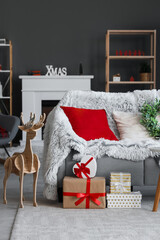 Interior of living room with sofa, Christmas presents and wooden reindeer