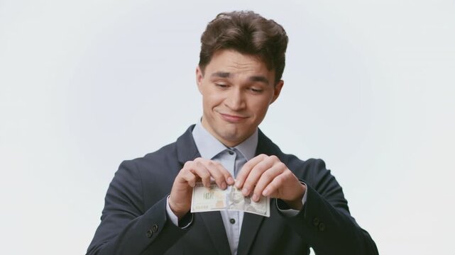 A young Caucasian man dressed in a suit stands against a plain background, exuding confidence and style. His expression suggests approachability and charm, reflecting a modern lifestyle.