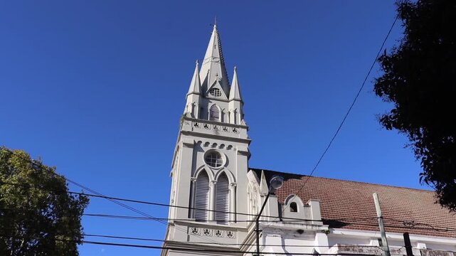 Gothic Revival tower of La Merced Church in Villa Ballester, Argentina. Soaring architecture against a clear blue sky on a sunny day