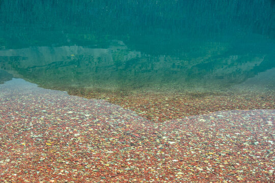 Fruity Pebbles Rocks Fade Into The Depts Of Elizabeth Lake In Glacier