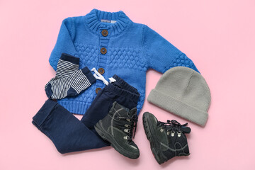 Stylish children's sweater, trousers, socks, hat and boots on pink background
