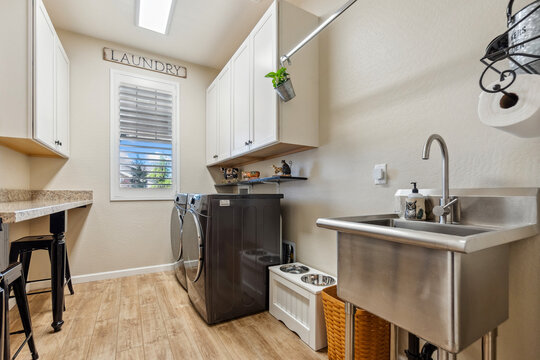 A laundry room with a sink, washer, dryer, and a window