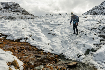 Hiker Carefully Climbs Down Snowy Bank In The Swiss Alps