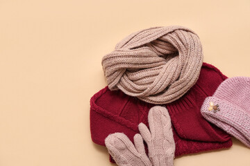Stylish children's sweater, scarf, hat and mittens on beige background