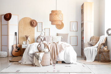 Interior of modern bedroom with comfortable bed, wicker armchair, shelving unit and guitar