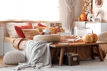 Comfortable bed, wicker poufs and bench in interior of modern bedroom