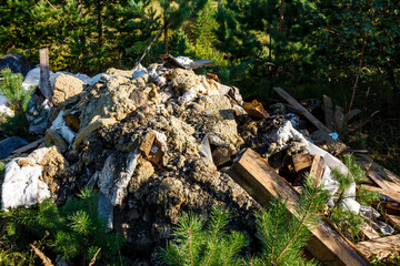 Unsightly pile of construction debris, dirt, and insulation dumped in a vibrant green forest, a stark image of environmental pollution and neglect