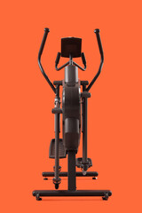 Modern elliptical machine on orange background