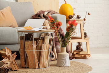 Book with autumn leaf on table and flowers in living room